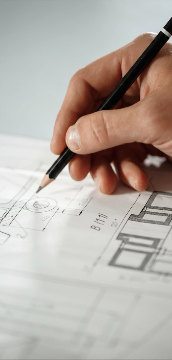 Mão a desenhar a lápis sobre uma planta de arquitetura